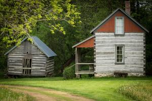 Two of the historic buildings at Norskedalen. One is small and grey and the other is taller with red siding on top.