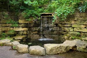 Waterfall surrounded by rocks with greenery above.